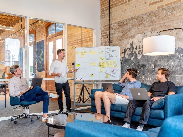 Men on couch watching a presenter on a whiteboard